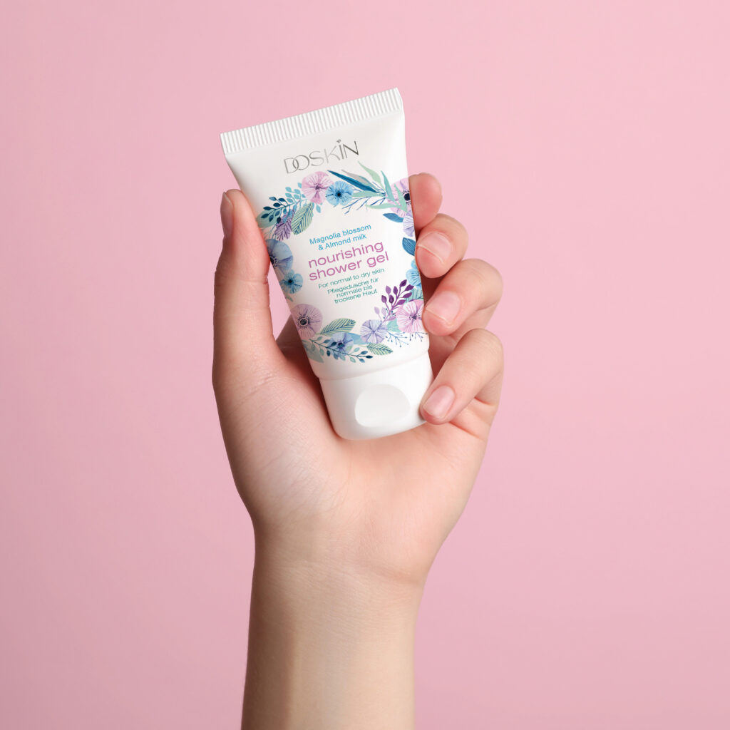 woman holding tube of face cream on pink background, closeup